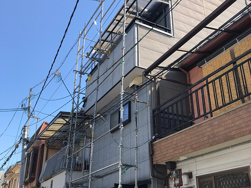 3階建て住宅のベランダ波板修理のため、建物全面に足場を組んだ施工中の様子