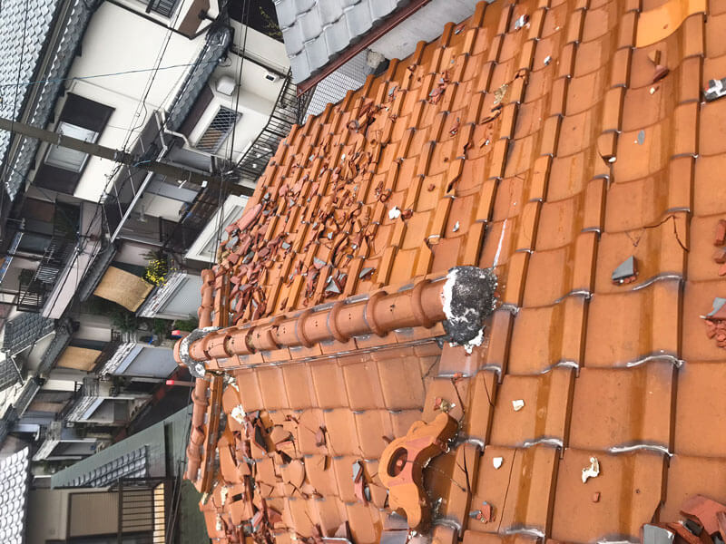 台風で隣家から飛んできた瓦で屋根瓦が割れている様子。