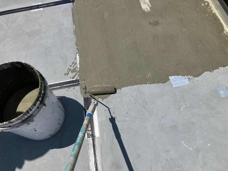 カチオン系モルタルで屋上の下地調整をしている様子