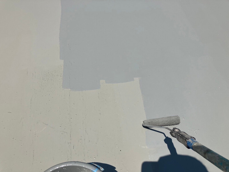 トップコートを屋上防水層の上に仕上げ塗りしている様子