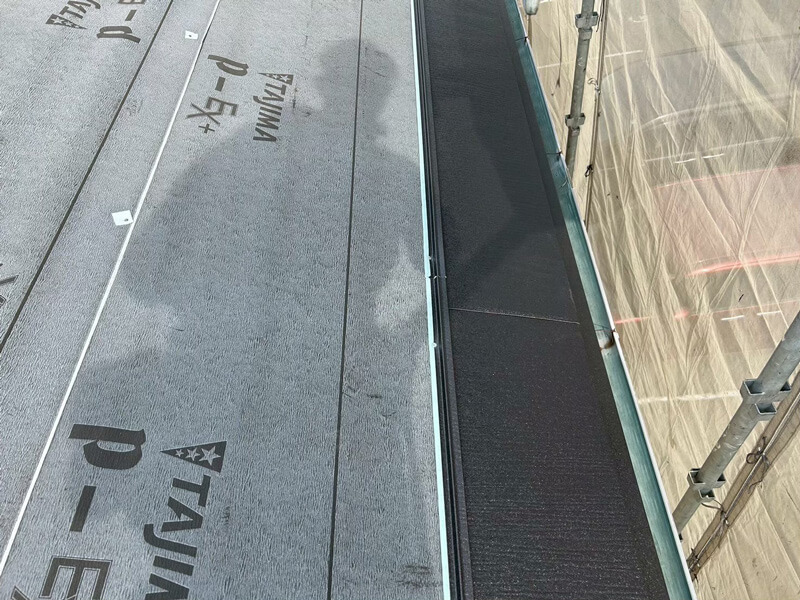 コロニアル屋根にルーフィングを敷きスーパーガルテクトを施工している様子