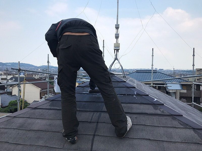 コロニアル屋根に下塗り塗料を施工している様子