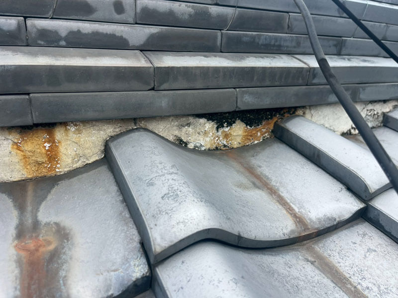 棟瓦下の漆喰剥がれと雨水染み・黒カビが見られる劣化箇所