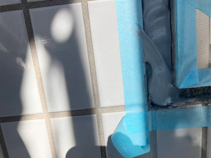 タイル外壁目地に新しいコーキング材を充填している施工中の写真