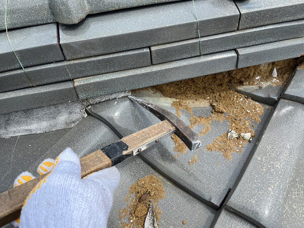 棟瓦周辺の古い漆喰を撤去している作業中の様子