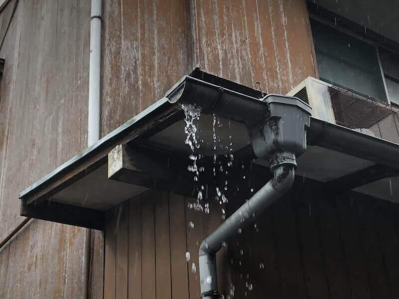 雨樋が詰まり、雨水があふれて落ちている様子の写真。