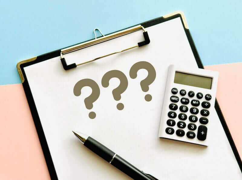 見積もりや費用の疑問をイメージした電卓とクリップボードの写真。