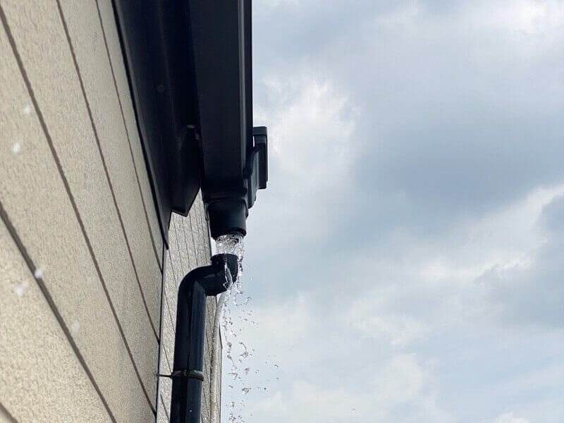 雨樋の縦樋が途中で外れて雨水がこぼれている様子。