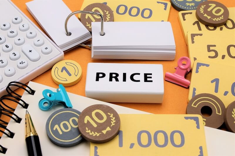 雨漏り修理費用の幅広い相場をイメージした写真。価格タグやコイン、電卓などが並ぶイメージ素材。