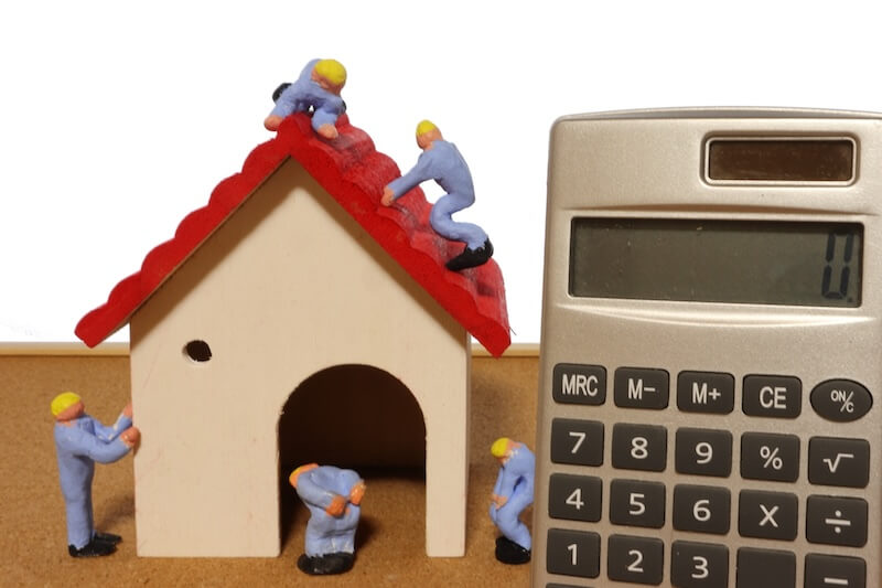 雨漏り修理費用をイメージした家模型と作業員、電卓の写真。
