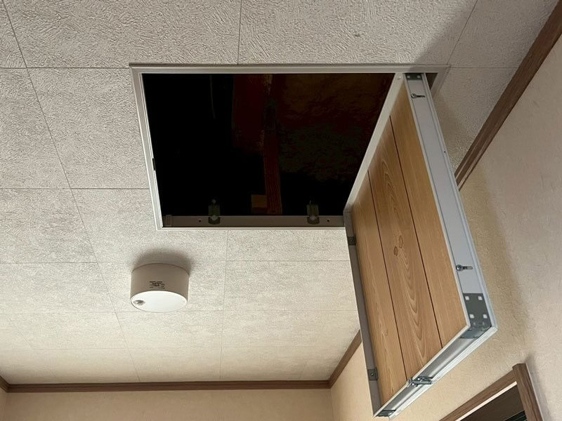 天井の点検口を開けて屋根裏を確認している様子