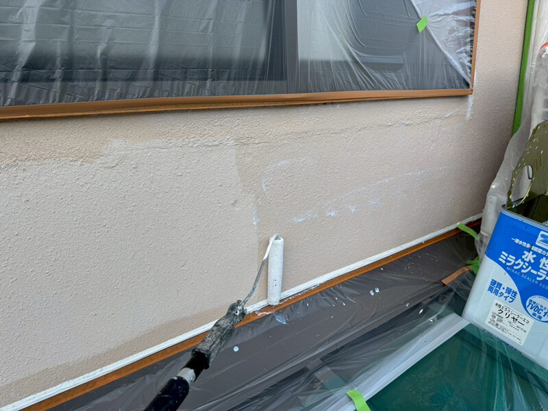 外壁の下塗り工程でシーラーをローラー塗布している作業中の写真