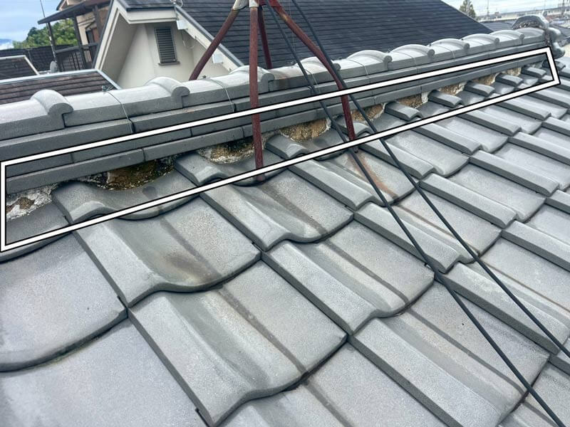 瓦屋根の棟部分で漆喰が剥がれ、内部の土が露出している施工前の状態。