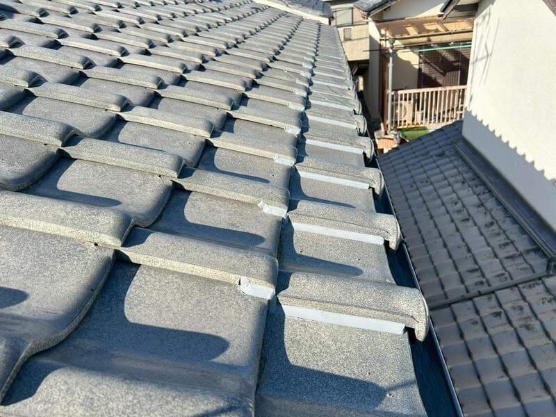 瓦屋根の軒先部分で、瓦のズレや脱落を防止するためのコーキング補強施工後の写真。